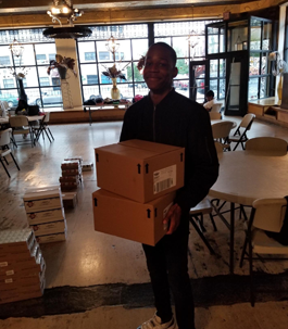 a smiling young man carrying boxes