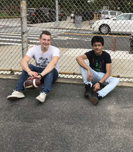 two boys sitting together outside